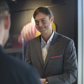 Ein Geschäftsmann im Anzug berät freundlich einen Kunden in einem modernen Geschäft.